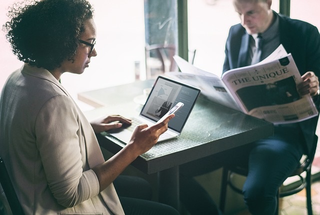 Restaurant Website Accessibility: People Sitting At A Table In A Restaurant While Looking At A Computer, A Phone And A Newspaper